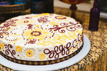 Bohemian birthday cake with yellow, red, and white decorations.