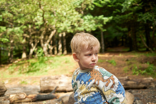 Boy standing near wooden logs trees
