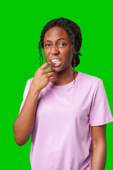 Young woman with curly hair looks uncomfortable while holding her mouth against a bright green...