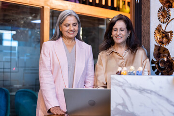 Happy Senior businesswomen discussing over laptop at desk in office