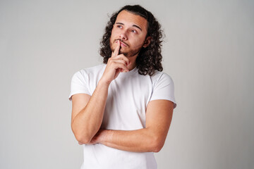 A man with curly hair thoughtfully pondering in a neutral background