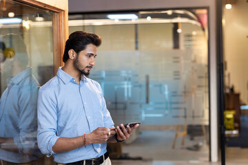 Handsome young modern businessman using digital tablet in the office