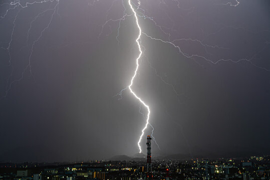 夜中に鉄塔の向こうの山に落雷する稲妻 - Powered by Adobe