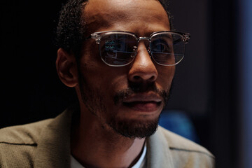 Obraz premium Portrait of man wearing eyeglasses and beard while looking intensely at computer screen in darkened environment