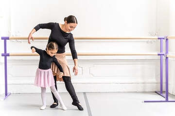 Happy ballerina teacher guiding young student in graceful ballet practice