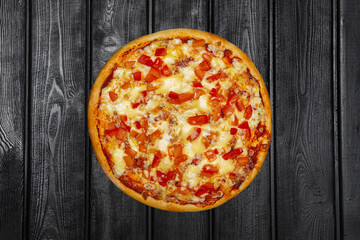 Pizza with bell pepper and cheese, top view, on black wooden background.
