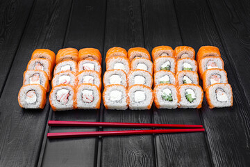 Mix, assorted Japanese sushi, rolls on a black wooden background.