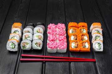 Mix, assorted Japanese sushi, rolls on a black wooden background.