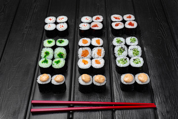 Mix, assorted Japanese sushi, rolls on a black wooden background.