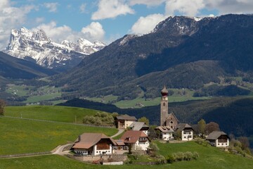 View of a picturesque village with a church tower,  with snow-capped mountains.