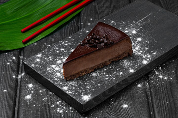 Chocolate cheesecake on black wooden background.
