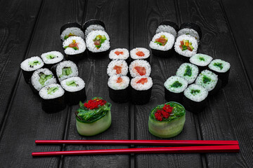 Mix, assorted Japanese sushi, rolls on a black wooden background.