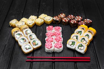 Mix, assorted Japanese sushi, rolls on a black wooden background.