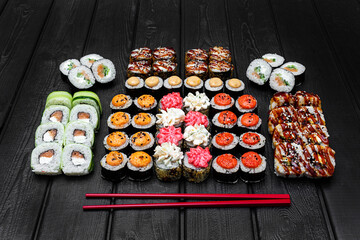 Mix, assorted Japanese sushi, rolls on a black wooden background.