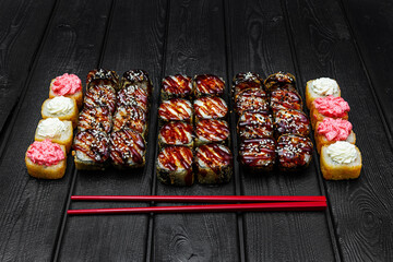 Mix, assorted Japanese sushi, rolls on a black wooden background.