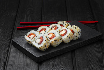 Japanese sushi, rolls with chicken and bell pepper on black wooden background.