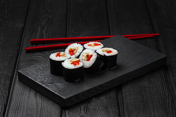 Japanese maki sushi with chicken and bell pepper on black wooden background.