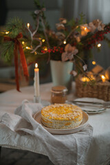 Festive Christmas tea time. Healthy cottage cheese cake with poppy seeds and almond petals on the table with a candle and Christmas decorations.
