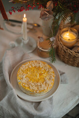 Overhead view of a healthy cottage cheese cake with poppy seeds and almond petals on the table with a candle and Christmas decorations.