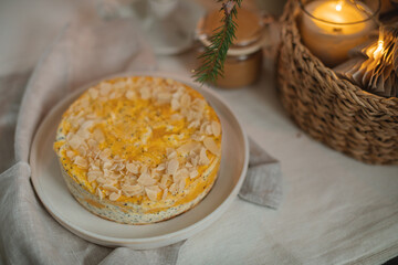 Close-up of a healthy cottage cheese pudding with poppy seeds and almond petals on the table with a candle and Christmas decorations.