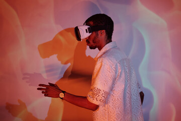 Man immersed in virtual reality, wearing headset, interacting with projected digital environment on colorful wall, showing modern technology experience