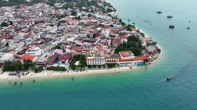 Aerial video view, flying around the tip area of historic Stone Town, the oldest part of Zanzibar Town on Unjuja island, Tanzania with historic buildings and beaches - video footage 