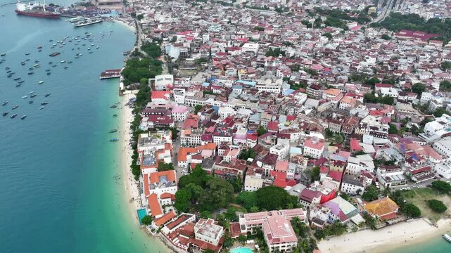 Aerial video footage of area around the historic Stone Town, the oldest part of Zanzibar Town on Unjuja island, Tanzania, starting at Shangani Beach, flying along historic buildings and landmarks 