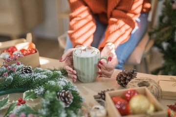 Woman holding cup of aromatic cocoa with marshmallows. Christmas eve with cup of tasty hot chocolate cozy holiday atmosphere at home
