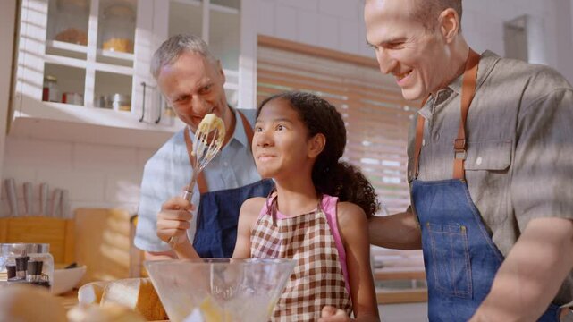Caucasian senior gay couple baking bakery with adopted daughter in house. 