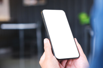 Mockup image of a woman holding and using mobile phone with blank desktop in cafe