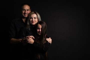 Happy young family with one child having fun together isolated on black.