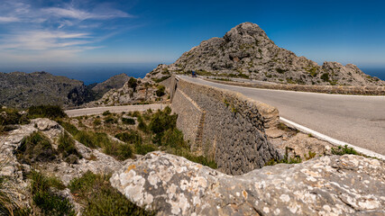 Mountain road MA-2141 at Nus de sa Corbata, where the road crosses itself in a twisting tie-knot formation, offering views of the Serra de Tramuntana mountains and Mediterranean Sea, ideal for cycling