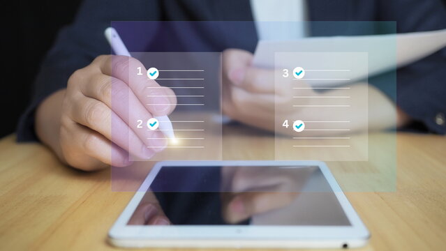 Businessman uses pen to choose or tick check marks checkboxes. Electronic survey form, checklist, fill out online form, electronic exam, and answer questions. Business performance monitoring concept.