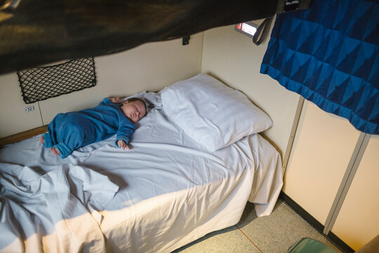 High angle view of boy sleeping on bed in sleeper train