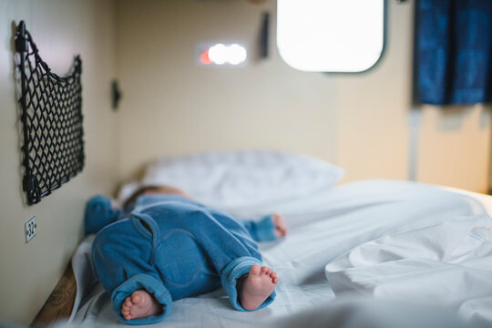 Boy with barefoot sleeping on bed in sleeper train