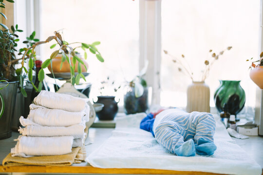 Newborn baby lying down near stack of reusable diapers at home