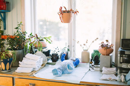 Newborn baby lying down near stack of reusable diapers by window