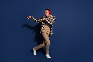 Fototapeta premium Full length photo of funky cool guy dressed plaid shirt earphones having fun emtpy space isolated blue color background