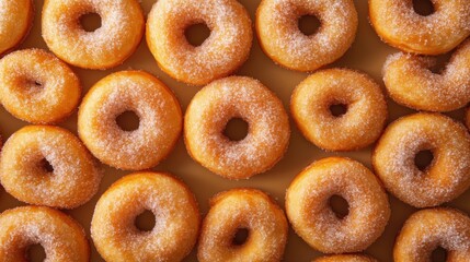 A surface densely covered with sugar-dusted donuts, filling every inch of the frame with their golden-brown, fluffy texture and sweet sugary coating.