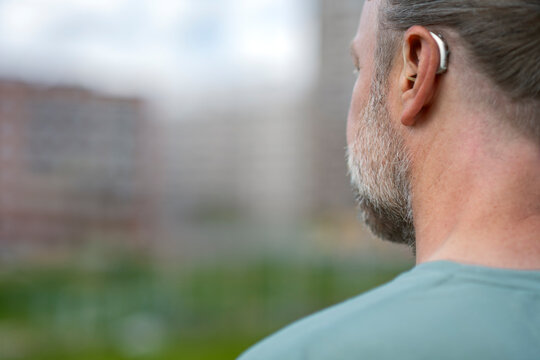 Rear view of man with gray beard wearing hearing aid device