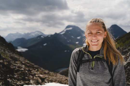 Portrait of smiling mid adult woman on mountain against cloudy sky