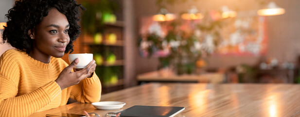 Dreamy african american young woman relaxing at cafe, drinking coffee or tea alone, copy space,...