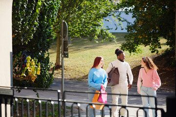 Happy male and female friends walking with shopping bags at street