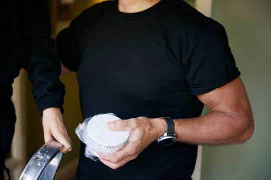 Midsection of man holding smoke detector