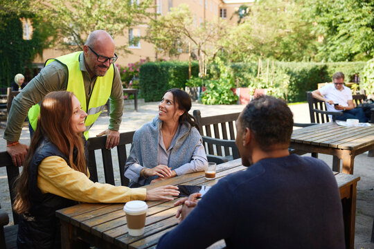 Happy male and female architects discussing with couple sitting on bench in garden