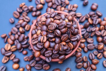 Robusta coffee beans or Coffea canephora in a wooden bowl and some scattered around it, close up view.