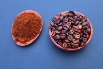 Robusta coffee beans or Coffea canephora in a wooden bowl and coffee powder in a wooden bowl. Close-up view, with dark background.