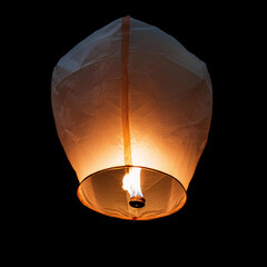 A single sky lantern isolated on black background. Rising in the dark night sky. single light in the darkness