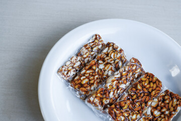 Snacks of peanuts and brown sugar wrapped in a clear plastic bag on a white plate. Isolated on white.