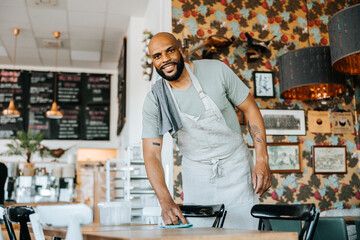 Portrait of waiter cleaning table in coffee shop